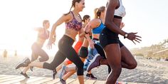 a group of women running on a boardwalk at the beach in front of the ocean