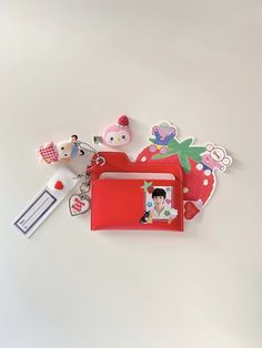 an assortment of items are displayed on a white surface, including a red card case and keychain