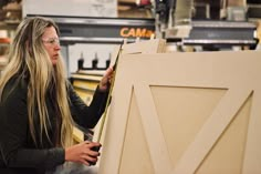 a woman is working on a piece of wood