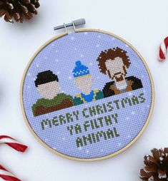 a cross - stitch christmas card with two men in the background and candy canes next to it