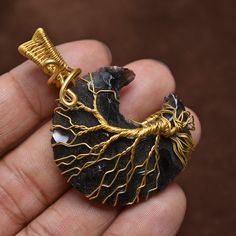 a person holding a piece of jewelry in their hand with the tree of life on it