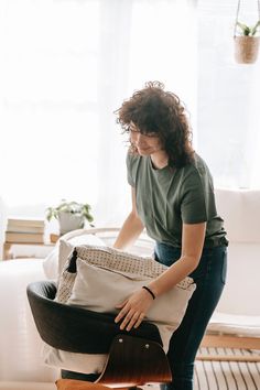 a woman holding a bag in her hand and standing next to a chair on the floor