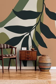 two chairs and a table in front of a wall with leaves painted on it