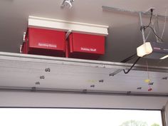 two red boxes are hanging from the ceiling in front of an open garage door,