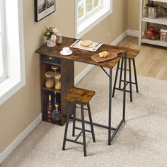 a small table with two stools next to it in front of a window on the floor