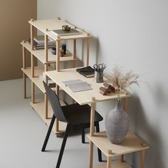 a wooden desk with two chairs next to it and a book shelf on the wall