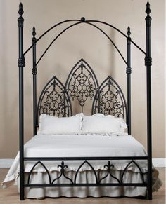 an iron bed frame with white sheets and pillows