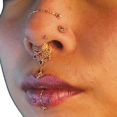 a woman's nose is adorned with gold jewelry and piercings on her nose