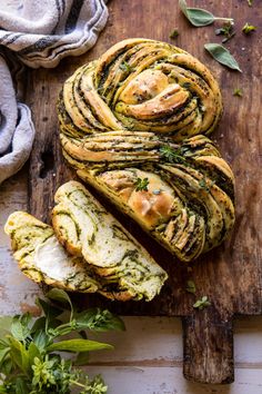 sliced garlic herb bread on a cutting board with herbs around it and the words, swirled garlic herb bread