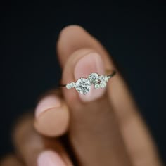 a woman's hand holding a three stone diamond ring