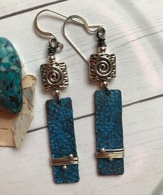 As blue as the water in the pool, these sunny, lightweight earrings combine Silver and Blue to perfection. The copper patina charms are textured and wrapped. The earrings measure 2-1/4 inches long. Silver findings and ear wires. Blue Artisan Copper Earrings, Artisan Blue Copper Earrings, Unique Blue Copper Earrings, Blue Copper Wire Wrapped Earrings, Artsy Blue Metal Jewelry, Artsy Nickel-free Blue Jewelry, Artsy Blue Nickel-free Jewelry, Blue Patina Earrings For Gift, Turquoise Copper Earrings