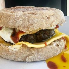 a close up of a sandwich on a plate with mustard and ketchup around it