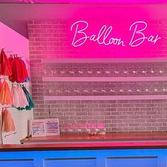 a pink neon sign that says balloon bar in front of a brick wall and counter