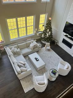 a living room with white furniture and a christmas tree