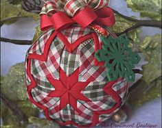 a christmas ornament hanging from a tree with red and green ribbon on it