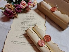 two wax seals are sitting on top of a piece of paper next to some flowers