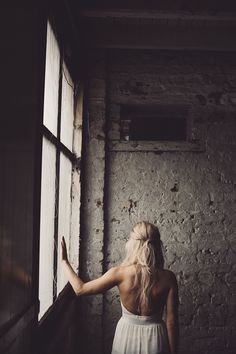 a woman standing in front of a window looking out