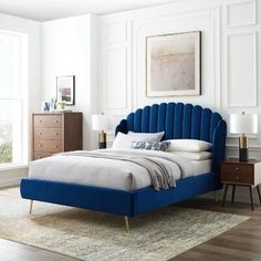 a bed with blue headboard and foot board in a white room next to a window