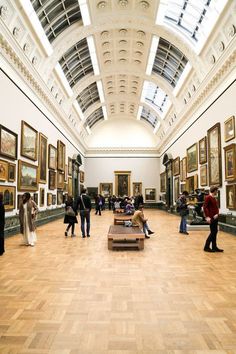 people are standing in an art gallery looking at paintings on the walls and ceiling,