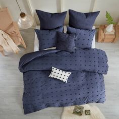 a bed with blue comforters and pillows on top of it, next to a white rug