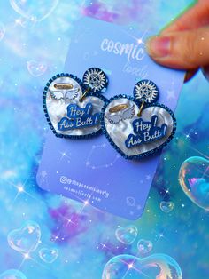 a pair of heart shaped earrings sitting on top of a card with bubbles floating around it