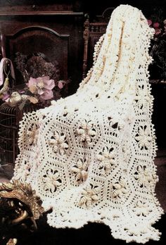 a white crocheted afghan sitting on top of a table next to a fireplace