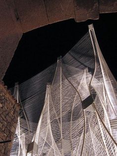 an artistic sculpture is shown at night with its lights on and wires running through it