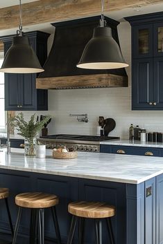 a large kitchen with blue cabinets and stools in the center, along with two pendant lights hanging from the ceiling