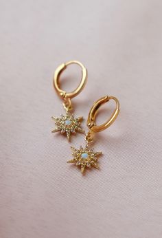 Experience the ethereal beauty of the Opalite Starburst Huggies. These huggie earrings feature stunning opalite stones in a delicate starburst design. With their subtle yet eye-catching sparkle, these earrings will add a touch of elegance to any outfit. Perfect for both everyday wear and special occasions. Materials: 14kt gold plated brass, cz star with synthetic opal, gold plated brass huggie Size: 10mm x 14mm SKU: E1630G Celestial Star-shaped Huggie Earrings With Star Charm, Celestial Star-shaped Gold Huggie Earrings, Gold Star-shaped Celestial Huggie Earrings, Gold Star Celestial Huggie Earrings, Gold Star Huggie Earrings In Celestial Style, Gold Star Shaped Huggie Earrings, Bachelorette Party Dress, Starburst Design, Rehearsal Dress