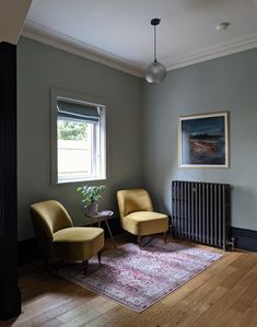 two yellow chairs sitting next to each other in front of a painting on the wall