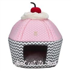 a pink and white cat bed with a cherry on top