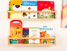 two wooden bookshelves with children's books on them against a white wall