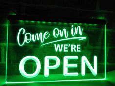 a green neon sign that says come on in we're open with the words