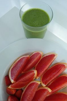 a white plate topped with slices of fruit next to a green smoothie