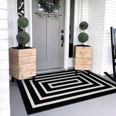 a black and white striped rug is on the front porch next to two planters