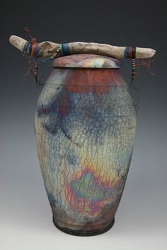 a vase with a wooden stick sticking out of it's top and colorful paint on the outside