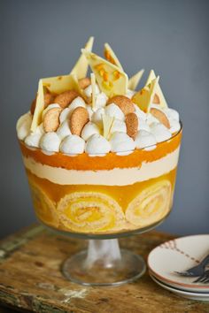 a cake with white and yellow icing sitting on top of a wooden table