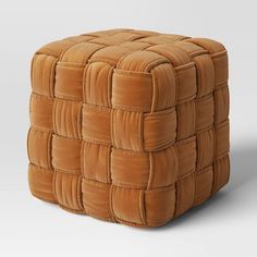 a small square ottoman made out of brown suede material with an interlocked design