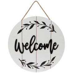 a sign that says welcome hanging from a rope on a white wall with black lettering