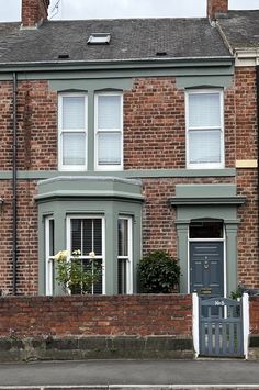 a brick house with white windows and green shutters