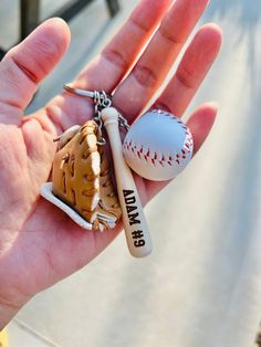 a hand holding a baseball, bat and glove keychain with the number 35 on it