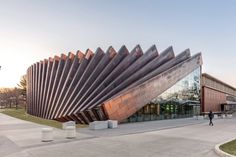 a building that has a large metal structure on it's face and is shaped like a wave