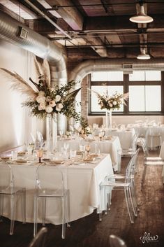 a room filled with lots of tables covered in white clothed tablecloths and chairs