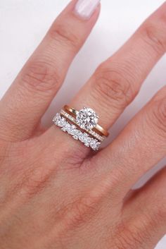 a woman's hand with two wedding rings on top of her ring and the middle finger