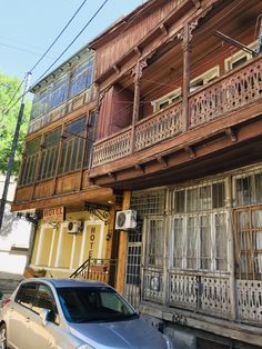 a car parked in front of an old wooden building with balconies on it