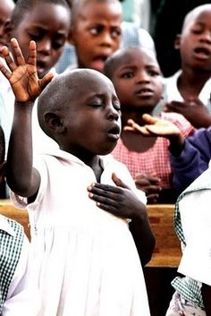 a group of young children standing next to each other with their hands up in the air