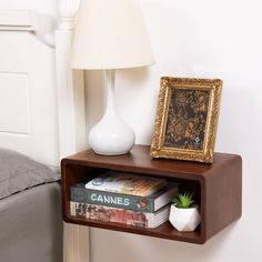 a shelf with books and a lamp on it next to a bed in a bedroom