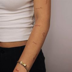 a woman's arm with tattoos on it and writing on the armbands