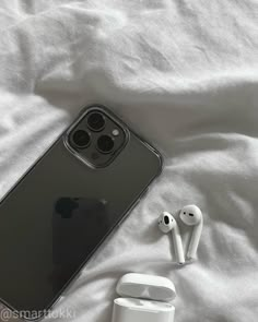 an iphone and ear buds laying on a bed