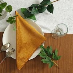 a white plate topped with a piece of cloth next to a fork and knife on top of a wooden table